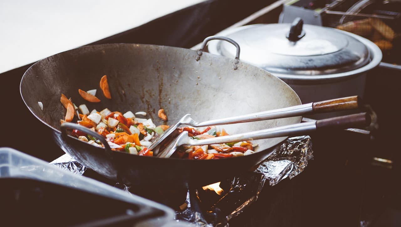 Wok cooking with vegetables in a professional Asian catering kitchen.